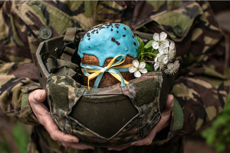 Voják drží přilbu s moučníkem a kytkou