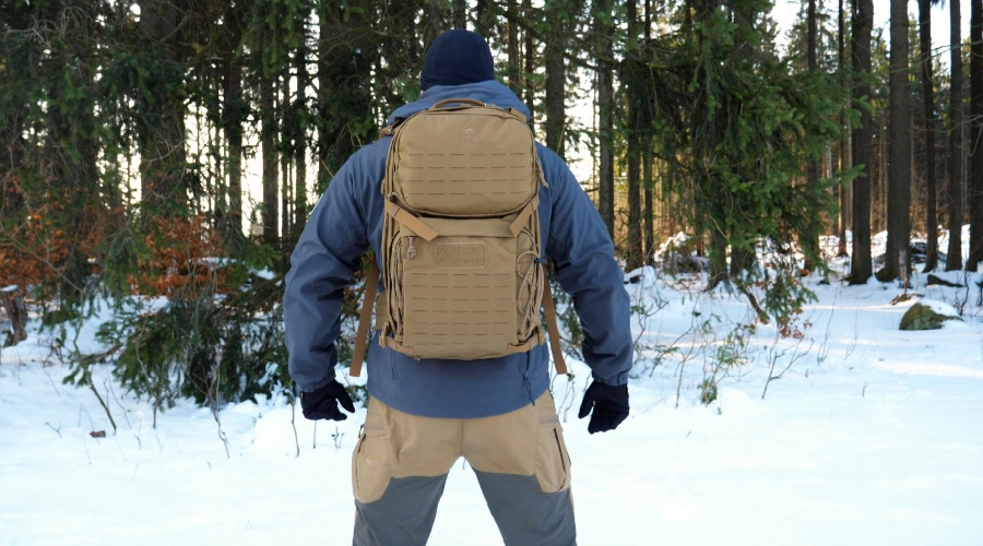 Muž v zimních kalhotech s batohem v zasněženém lese