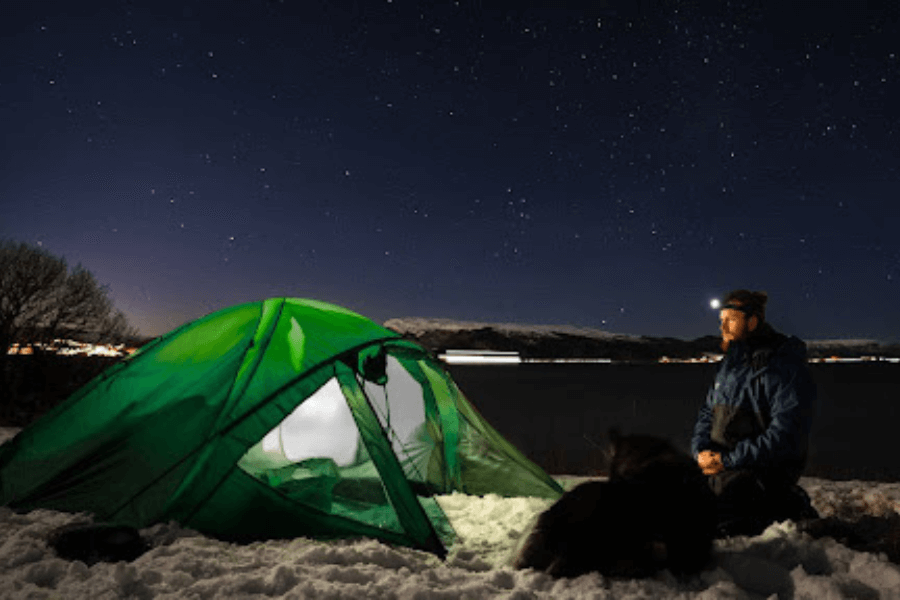 Man in front of tent, camping in the snow.