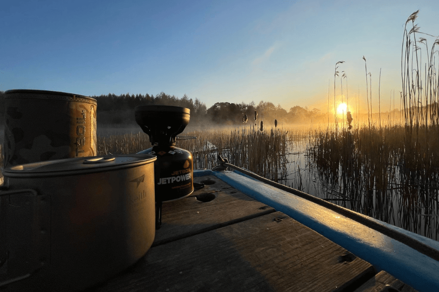 Vařič Jetboil a nádobí Keith u vody v Estonsku při východu slunce