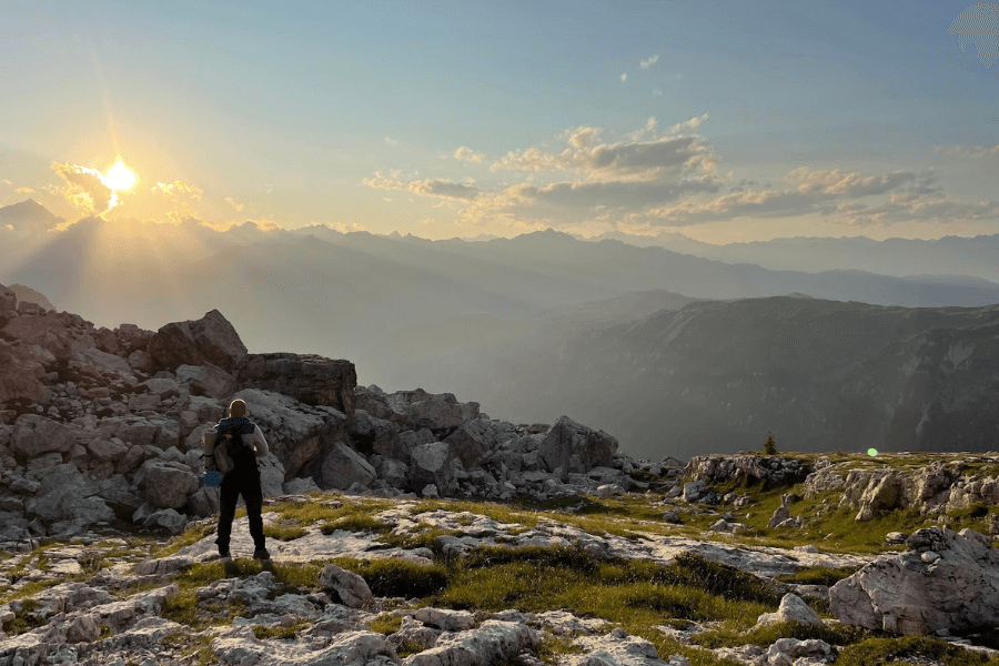 Muž na horách sleduje východ slunce