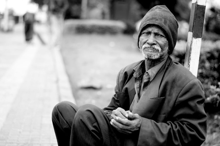 Starý muž sedící na zemi na ulici