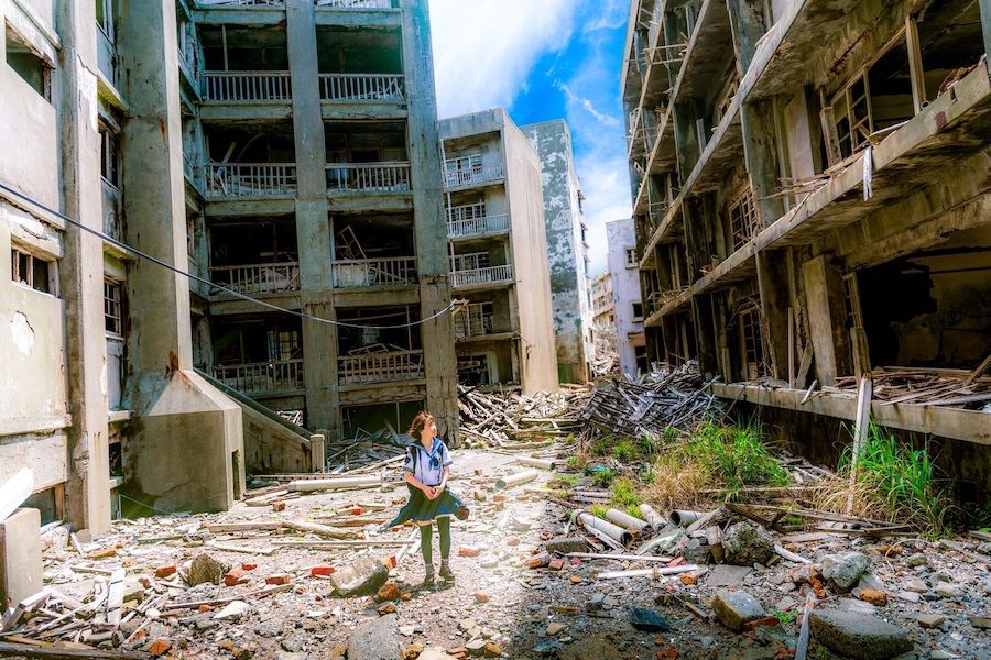 Dívka chodící mezi zničenými budovami