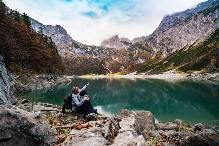 Lidé sedící u jezera v horách